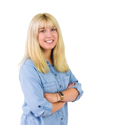 Carola Tietzsch: Frau mit langen blonden Haaren, trägt hellblaues Jeanshemd, verschränkt die Arme.